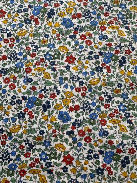 Patterned fabric with small flowers in red, blue, yellow, and green on a white background