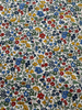 Patterned fabric with small flowers in red, blue, yellow, and green on a white background